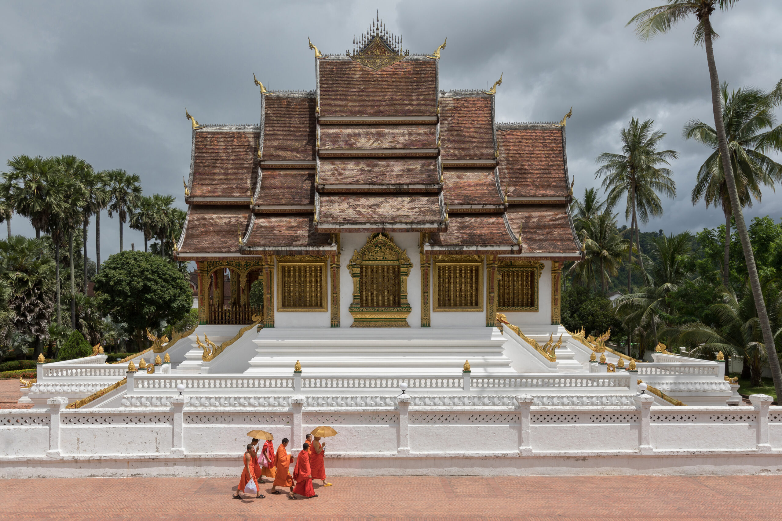 Ancestral Arts & Craftsmanship 8 Buddhist monks walking in front of the temple Haw Pha Bang in Luang Prabang scaled