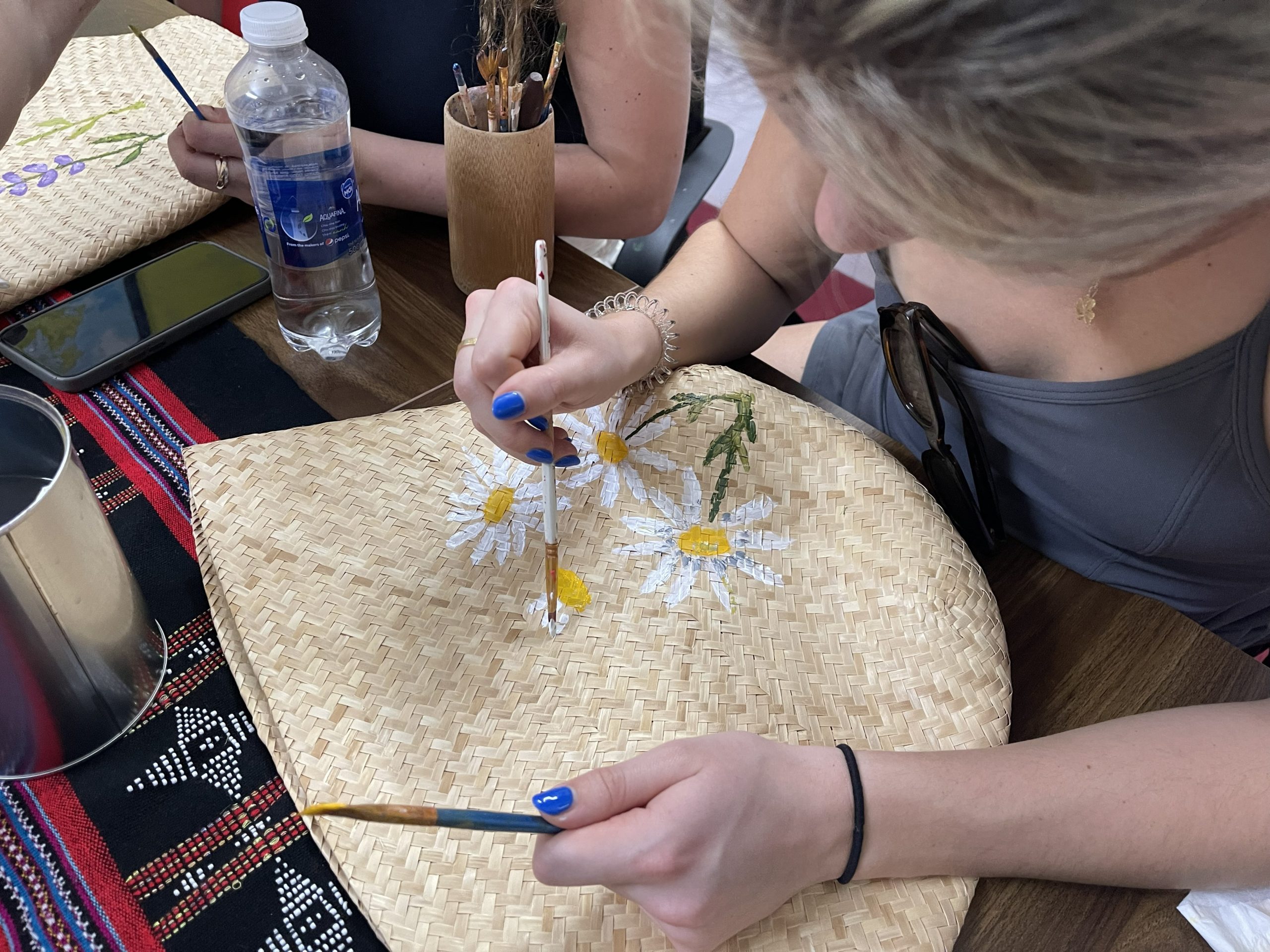 A student learn how to draw on a straw bag