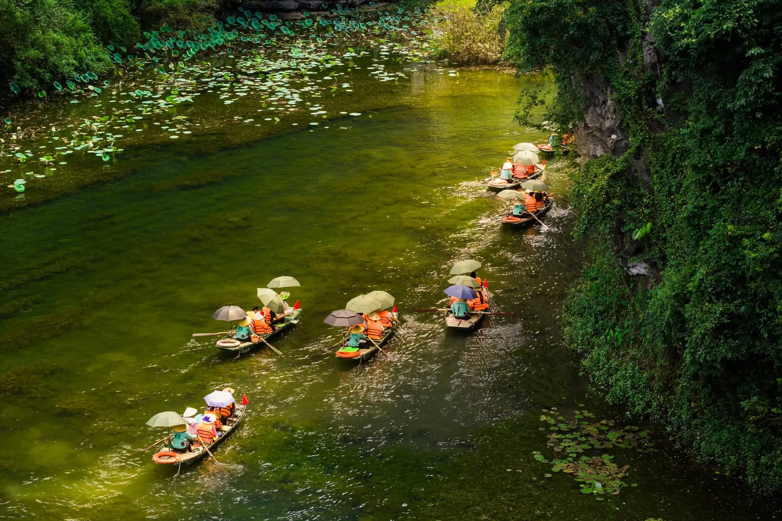 Rowing boats carry tourists slowly passing the caves