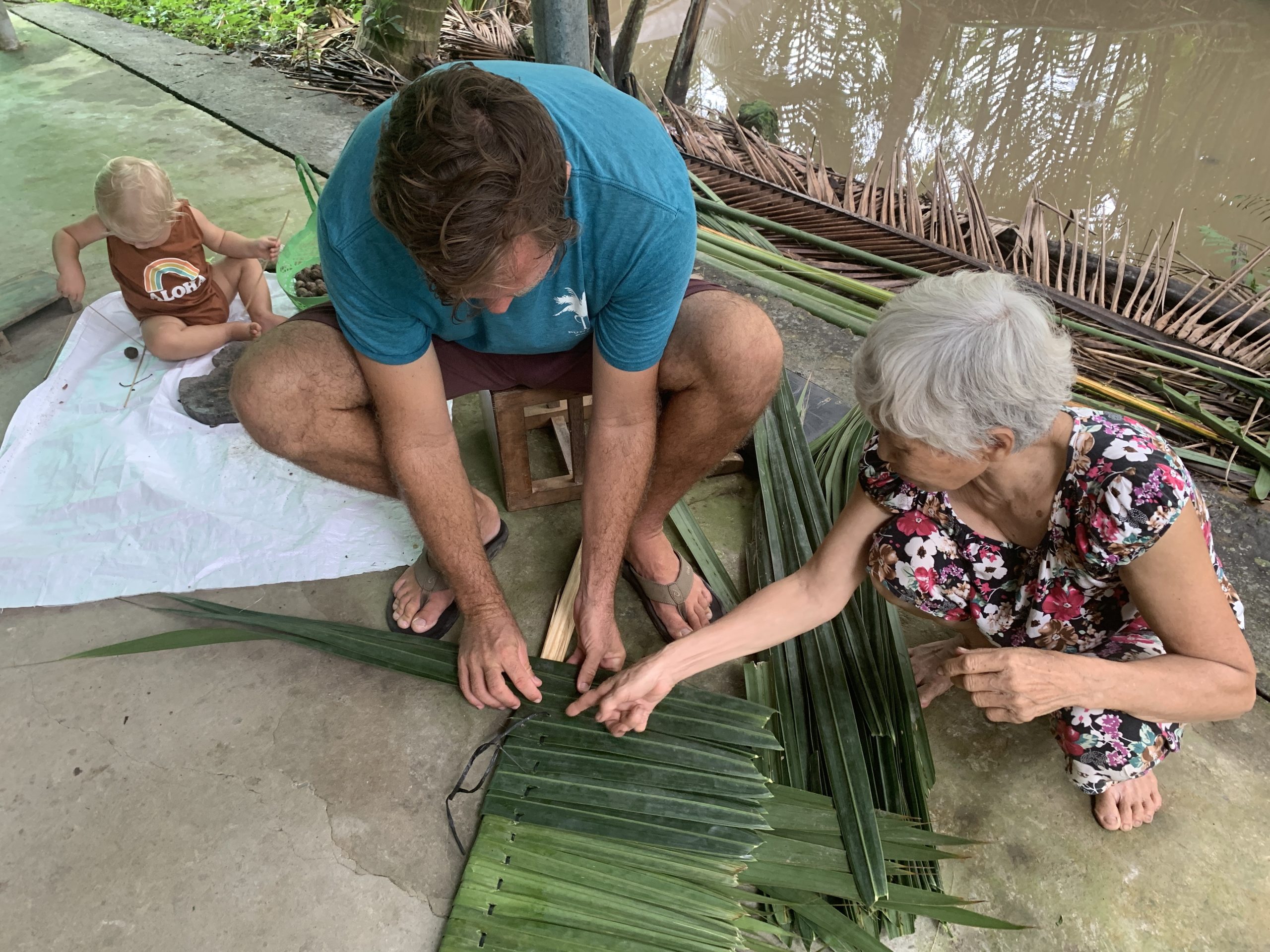 guests learn to weave coconut leaf to make a thatched roof